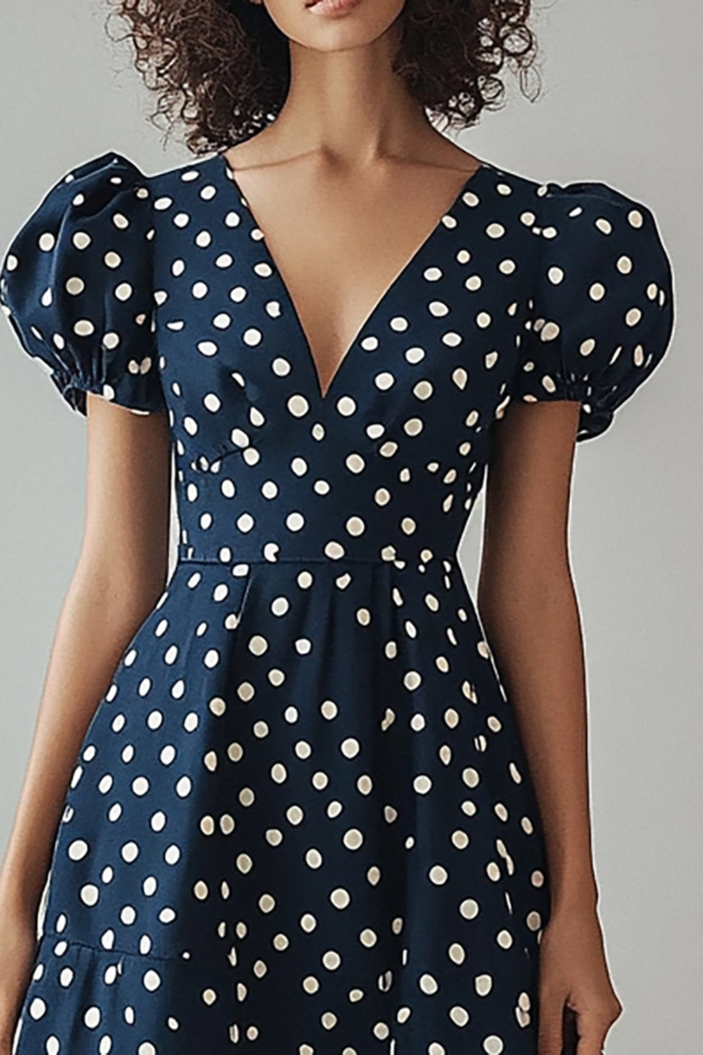 Une robe à pois blancs marine à col en V avec manches bouffantes