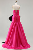 Robe de soirée longue en satin fuchsia coupe bustier à décolleté cabriolet avec grand nœud