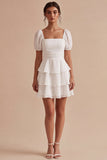 Une mini-robe blanche à volants à niveaux, à manches bouffantes