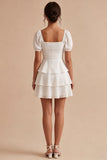 Une mini-robe blanche à volants à niveaux, à manches bouffantes