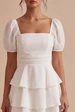 Une mini-robe blanche à volants à niveaux, à manches bouffantes