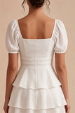 Une mini-robe blanche à volants à niveaux, à manches bouffantes
