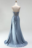 Robe de soirée gris bleu en satin avec un corset à strass, un effet de transparence et des fronces, à fines bretelles avec une fente