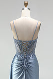 Robe de soirée gris bleu en satin avec un corset à strass, un effet de transparence et des fronces, à fines bretelles avec une fente