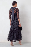 Robe invitée mariage midi noire coupe sirène, à col rond illusion, détails floraux, volants et manches 3/4